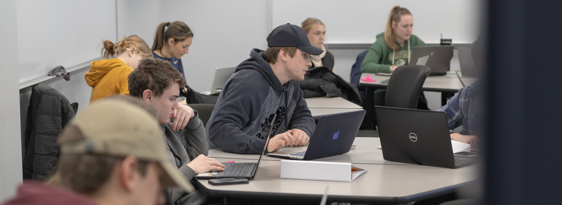 students learning and taking notes on their laptops in a classroom