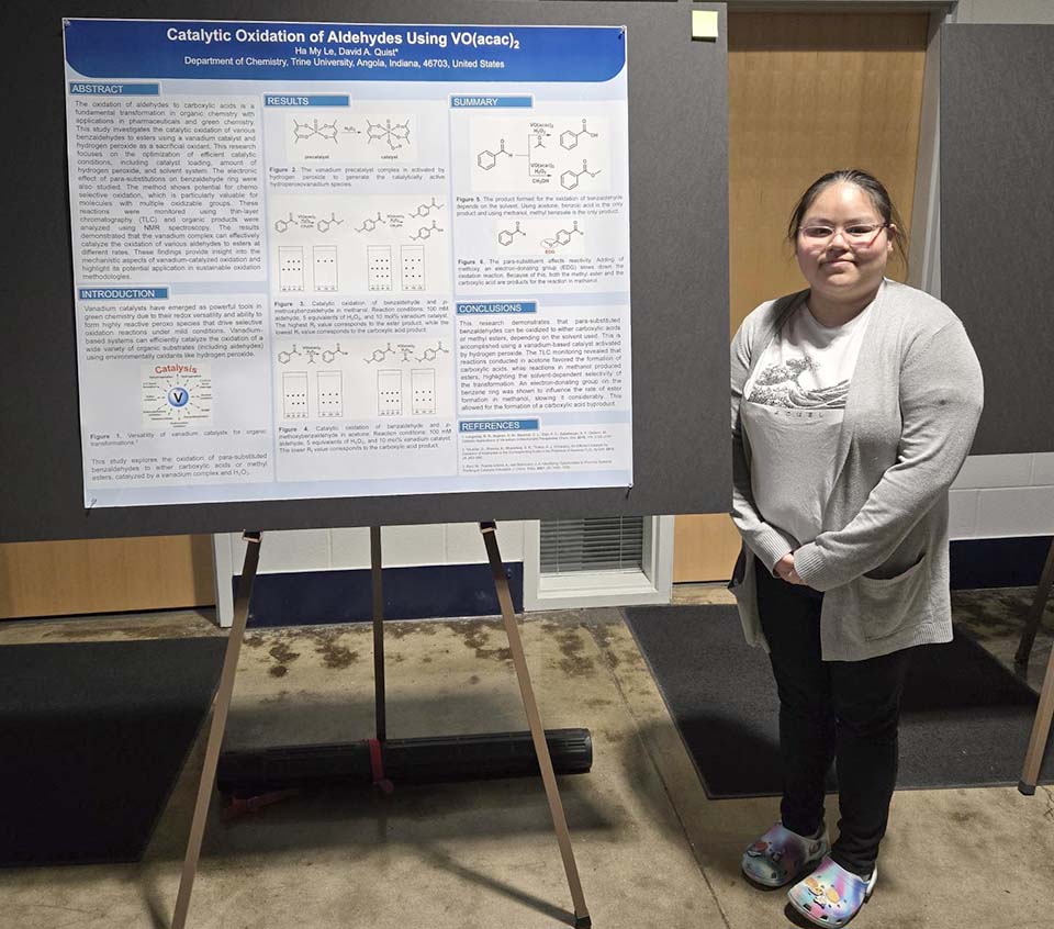 Trine University student with chemistry research poster