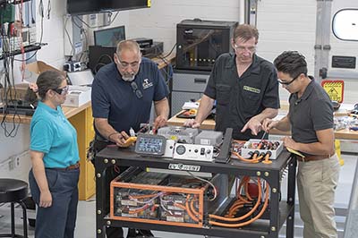 Trine faculty with Mark Weller undergoing training on the EV Trainer Cart.