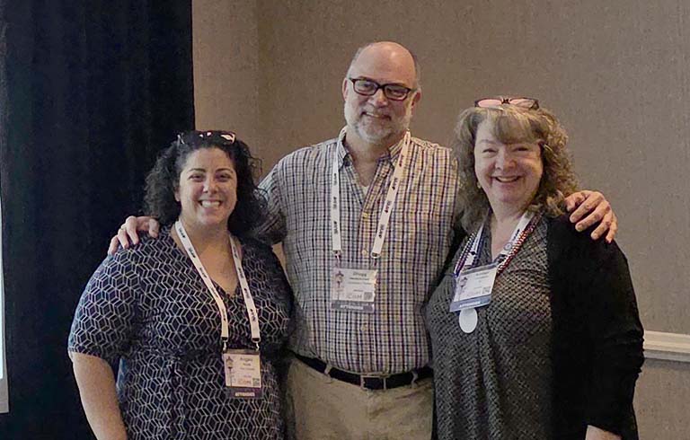 Three presenters standing together with name badges