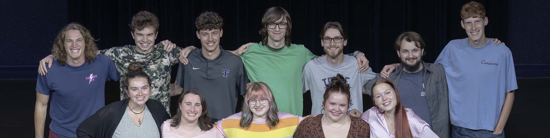 Cast in two rows on theatre stage