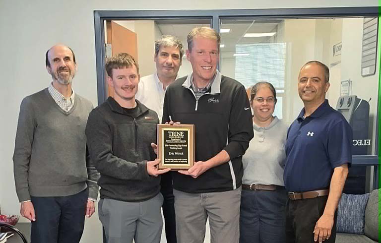 Student handing award to teacher with faculty standing behind
