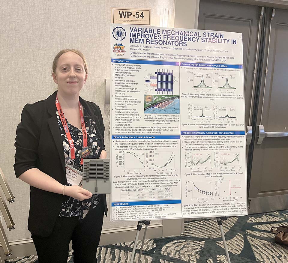 Student holding device and standing to left of research poster