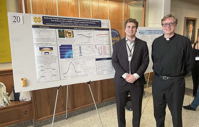Keiton Klein and Fr. Bryan Paulsen, S.J., Ph.D., next to a research poster