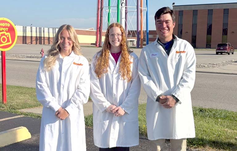 Three students standing in lab coats