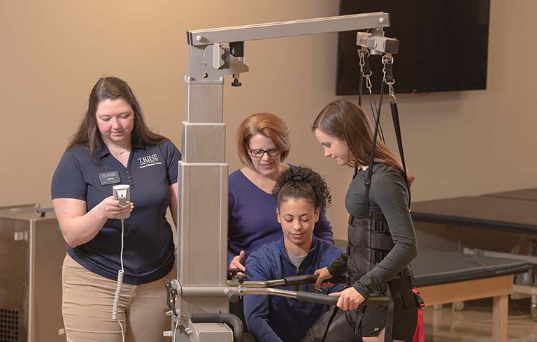 Students and a faculty member working with physical therapy equipment